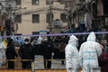 中国・上海の黄浦区で、隔離対象となった住宅街周辺を封鎖する防護服姿の警察官ら（2021年1月21日撮影）。(c)STF / AFP
