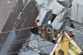 地震で倒壊した台湾南部・台南市の集合住宅で、がれきの中から救出された8歳の少女を運び出す救助隊員たち（2016年2月8日撮影）。(c)AFP/SAM YEH