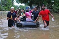 インド南部ケララ州コジコーデの住宅地で、住民らをボートに乗せて避難させるボランティアや救助隊（2018年8月16日撮影）。(c)AFP