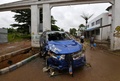 コートジボワールのアビジャンで、車の残骸のそばを歩く人々（2018年6月19日撮影）。(c)AFP PHOTO / Sia KAMBOU