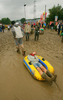 2007年6月23日、サマセット（Somerset）のピルトン（Pilton）で開催されている「グラストンベリー・フェスティバル（Glastonbury Festival）」で泥の上をボートに引かれて運ばれる来場者。(c)AFP/CARL DE SOUZA