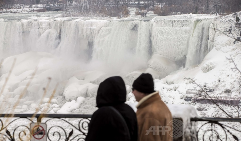 凍り付いたナイアガラの滝に集まる観光客ら