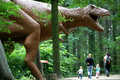 ドイツ東部バウツェン（Bautzen）近郊にある恐竜公園で、大型肉食恐竜ティラノサウルスの想像復元模型の横を通る親子連れ（2007年7月25日撮影）。(c)AFP/AIZAR RALDES