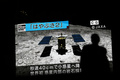 宇宙航空研究開発機構（JAXA）の小惑星探査機「はやぶさ2」のCG画像を映した画面の前を歩く人（2019年7月10日撮影、資料写真）。(c)Behrouz MEHRI / AFP