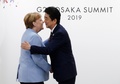大阪で開催中の20か国・地域（G20）首脳会議の歓迎行事で、アンゲラ・メルケル独首相（左）を迎える安倍晋三首相（右、2019年6月28日撮影）。(c) Eugene HOSHIKO / POOL / AFP