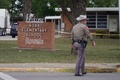 銃乱射事件が起きた米テキサス州ユバルディのロブ小学校前を歩く警察官（2022年5月24日撮影）。(c)allison dinner / AFP