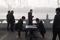 スモッグに覆われた中国・北京の湖畔で、中国将棋に興じる男性2人（2017年1月1日撮影）。(c)AFP/GREG BAKER
