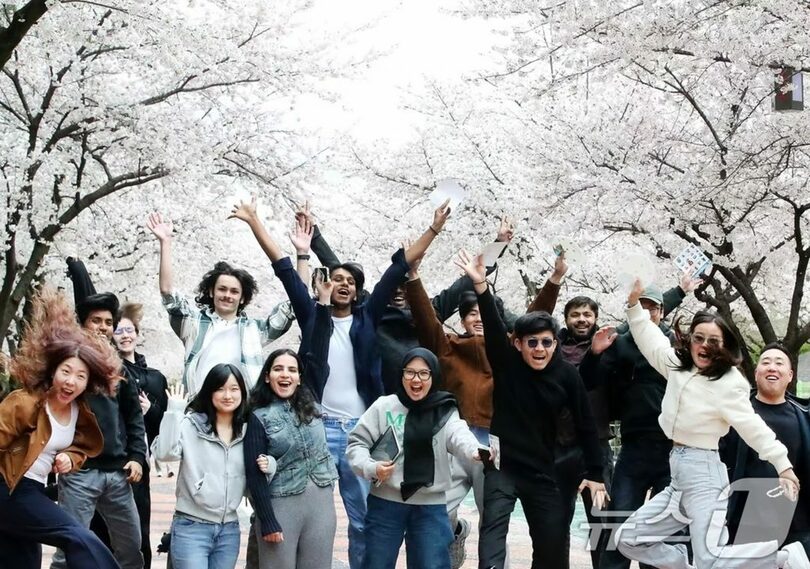 満開の桜を背景に記念撮影する外国人観光客(c)news1