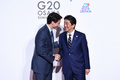大阪で開催された20か国・地域（G20）首脳会議（サミット）で、カナダのジャスティン・トルドー首相を歓迎する安倍晋三元首相（2019年6月28日撮影）。(c)Brendan Smialowski / AFP