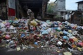 スリランカ・コロンボで、路上のごみ山の上を歩く男性（2017年6月26日撮影）。(c)AFP/ISHARA S. KODIKARA