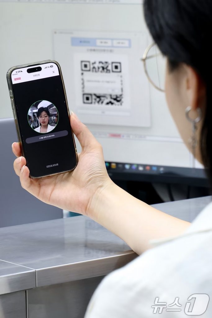 ソウル市内の携帯電話販売店で、契約時に適用される顔認証の手順を実演する店員(c)news1