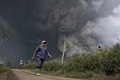 インドネシアの北スマトラ（North Sumatra）州カロ（Karo）で、村を飲み込んだシナブン山（Mount Sinabung）の噴火による高温の火山灰雲から逃れる住民（2014年2月1日撮影）。(c)AFP/CHAIDEER MAHYUDDIN