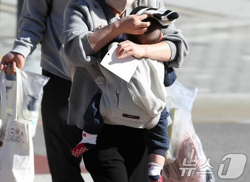 2025年12月、寒さから赤ちゃんを守るため毛帽子をかぶせる母親(c)news1