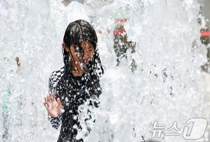 ソウルの昼の最高気温が30度を超える暑さとなった18日、ソウル市鍾路区の光化門広場の噴水で水遊びをする子どもたち(c)news1