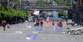 タイの首都バンコク（Bangkok）で有刺鉄線が張られた道路をオートバイで通行する人々（2010年5月15日撮影）。(c)AFP/PORNCHAI KITTIWONGSAKUL