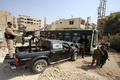 シリア・ダラヤを撤退する人々を乗せたバスのそばで警戒に当たるシリア政府軍の兵士ら（2016年8月26日撮影）。(c)AFP/Youssef KARWASHAN
