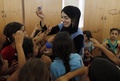 パレスチナ自治区ガザ地区（Gaza Strip）北部ジャバリヤ（Jabaliya）の避難所として使われている学校で、国連（UN）のプログラムの一環として心に傷を負った子どもたちの支援に当たるボランティアの女性と、その周りに集まる子どもたち（2014年8月2日撮影）。(c)AFP/MOHAMMED ABED