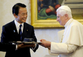 8日からイタリア・ラクイラ（L&apos;Aquila）で開催される主要8か国（G8）首脳会議参加のため同国入りした麻生太郎（Taro Aso）首相は7日、バチカン市国を訪問し、ローマ法王ベネディクト16世（Benedict XVI）と会談した。写真は、内謁中、法王（右）にビデオカメラを贈る麻生首相（2009年7月7日撮影）。(c)AFP/DANILO SCHIAVELLA