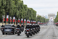 フランス・パリのシャンゼリゼ通りで行われたフランス革命記念日の軍事パレードで、車の中から手を振る同国のエマニュエル・マクロン大統領（左、2019年7月14日撮影）。(c)LUDOVIC MARIN / POOL / AFP