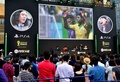 都内で行われた家庭用ゲーム機「プレイステーション4（PlayStation 4、PS4）」用サッカーゲーム「FIFA 14  2014 FIFA World Cup Brazil  Limited Pack」の発売イベントで、大型スクリーンに映ったゲーム画面を眺めるサッカーファンら（2014年6月4日撮影）。(c)AFP/Yoshikazu TSUNO