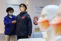 北京冬季五輪の関係者が着用する防護服を試着する女性（右）。中国・山東省浜州市の工場で（2022年1月27日撮影）。(c)AFP