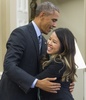米ワシントンD.C.（Washington D.C.）ホワイトハウス（White House）の大統領執務室（Oval Office）で、エボラ出血熱から回復した看護師のニーナ・ファム（Nina Pham）さん（右）を抱きしめるバラク・オバマ（Barack Obama）米大統領（左、2014年10月24日撮影）。(c)AFP/Saul LOEB