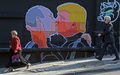 リトアニアの首都ビリニュスで、キスをするドナルド・トランプ氏とウラジーミル・プーチン大統領が描かれた壁画の前を歩く人々（2016年5月13日撮影）。(c)AFP/Petras Malukas
