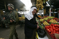 2008年4月13日、パレスチナ自治区ヨルダン川西岸（West Bank）ヘブロン（Hebron）旧市街の果実市場と、巡回にあたるイスラエル軍兵士。(c)AFP/HAZEM BADER
