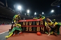 ロンドン五輪、陸上男子4×100メートルリレー決勝。世界新記録を示す電光掲示の横でポーズを取るジャマイカの選手（2012年8月11日撮影）。(c)AFP/FRANCK FIFE