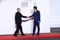 大阪で開催中の20か国・地域（G20）首脳会議の歓迎行事で、ロシアのウラジーミル・プーチン大統領（左）を迎える安倍晋三首相（右、2019年6月28日撮影）。(c)Brendan Smialowski / AFP