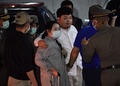 タイの首都バンコクで、警察署に到着し、母親に付き添われる民主活動家のパリット・チワラック氏（中央右側、2020年8月14日撮影）。(c)Lillian SUWANRUMPHA / AFP