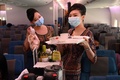 シンガポールのシンガポール（チャンギ）国際空港に駐機された、シンガポール航空の旅客機内に期間限定で開かれたレストランで、笑顔を振りまく客室乗務員（2020年10月24日撮影）。(c)ROSLAN RAHMAN / AFP