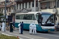 中国・上海の黄浦区の隔離対象となった住宅街で、バスのそばに立つ防護服姿の警察官ら（2021年1月21日撮影）。(c)STF / AFP