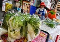 タイの首都バンコクで、プラスチック袋に入れた野菜を売る人（2020年6月27日撮影）。(c)Romeo GACAD / AFP