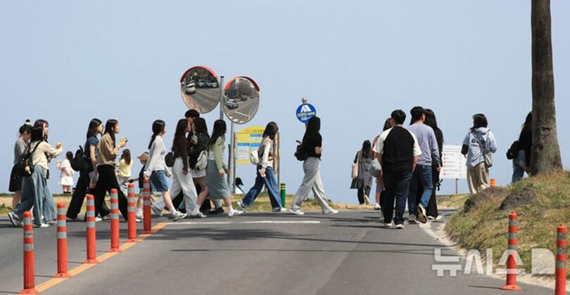 済州・咸徳海水浴場付近で集団で横断する修学旅行中の生徒ら(c)NEWSIS