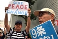 横浜市で開かれた安全保障関連法案に関する地方公聴会の会場前でプラカードを掲げて同法案に抗議する人々（2015年9月16日撮影）。(c)AFP/Yoshikazu TSUNO