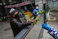 中国中部・湖北省武漢で、ゲート越しに野菜の代金を支払う住民（2020年3月3日撮影）。(c)AFP