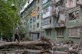 早朝、ロシア軍の攻撃で破壊された建物の外に集まる住民。ウクライナ東部ドネツク州コンスタンチノフカで（2022年8月6日撮影）。(c)Bulent KILIC / AFP