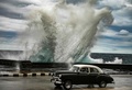 キューバ・ハバナで、強風で波しぶきが上がる海沿いの道路を走る古い米国製の車（2022年2年9日撮影）。(c) YAMIL LAGE / AFP