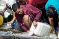 ベネズエラの首都カラカスで、破裂した水道管から下水用水路へと流れ込む水をくむ人たち（2019年3月11日撮影）。(c)JUAN BARRETO / AFP