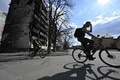ウクライナの首都キーウ近郊のイルピンで、損傷した住宅ビルのそばを自転車で走る地元住民（2022年4月24日撮影、資料写真）。(c)Genya SAVILOV / AFP