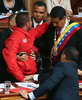 ベネズエラの首都カラカス（Caracas）で行われた大統領の就任宣誓式で、演壇でニコラス・マドゥロ（Nicolas Maduro）新大統領（右）を押しのけた赤いジャケットの男を取り押さえるディオスダド・カベジョ（Diosdado Cabello）国民議会議長と警備員の男性（中央後ろ、2013年4月19日撮影）。(c)AFP/Francisco Boza