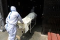 インドの首都ニューデリーにある火葬場で、コロナ犠牲者の遺体を運ぶ防護服姿の作業員（2020年6月3日撮影）。(c)AFP/Sajjad  HUSSAIN