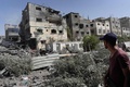 パレスチナ自治区ガザ地区中部ヌセイラットで、イスラエル軍の作戦後、損傷した建物を見るパレスチナ人（2024年6月8日撮影）。(c) Bashar TALEB / AFP