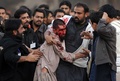 イスラム教シーア派の宗教行事「アシュラ（Ashura）」が行われ、シーア派とスンニ派の衝突が発生したパキスタン・ラワルピンディ（Rawalpindi）で、衝突で負傷したスンニ派の男性を支えるシーア派のイスラム教徒ら（2013年11月15日撮影）。(c)AFP/Aamir QURESHI