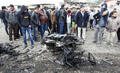 イラクの首都バグダッドのサドルシティーで、爆発現場にある焼け焦げた自動車の周囲に集まった人々（2017年1月2日撮影）。(c)AFP/SABAH ARAR