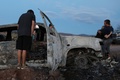 メキシコ・ソノラ州の山岳地帯で襲撃されたモルモン教徒の家族が乗っていた車の前で頭を垂れる遺族（2019年11月5日撮影）。(c)HERIKA MARTINEZ / AFP
