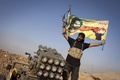 イラク北部サラハディン（Salaheddin）州ツズフルマツ（Tuz Khurmatu）で起きたイスラム教スンニ派（Sunni）の過激派組織「イスラム国（Islamic State、IS）」との激しい衝突で、ロケット弾発射装置
の隣で旗を振るシーア派（Shiite）民兵（2014年8月31日撮影）。(c)AFP/JM Lopez