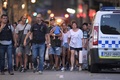 スペイン・バルセロナのランブラス通りで発生した襲撃事件で、警官に付き添われて規制線の外に出る買い物客（2017年8月17日撮影）。(c)AFP/LLUIS GENE