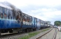 インド東部ビハール（Bihar）州カガリア（Khagaria）で巡礼者に突っ込む事故を起こした鉄道の客車。感情的になった群集により火を放たれ煙が上がっている（2013年8月19日撮影）。(c)AFP